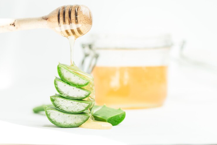 Close-up of aloe vera slices and honey by jar on table