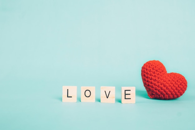 Photo close-up of alphabets and woolen heart shape over blue background