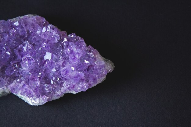 Close-up of amethyst stone druse crystals on dark granite\
polished slab. texture of crystals of amethyst. amethyst crystals\
geological mineral background. selective focus.