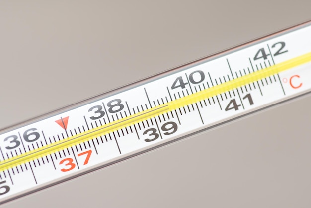Close up of an analogue thermometer on grey background