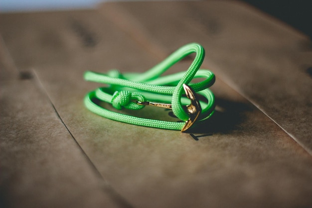 Foto close-up di un pendente di ancoraggio con una corda verde su un tavolo di legno