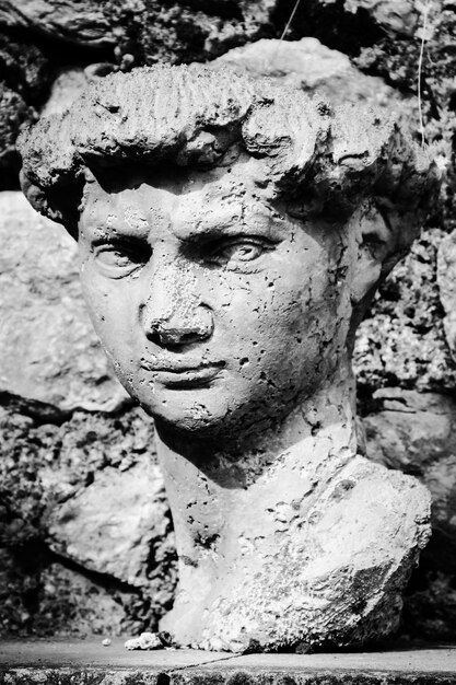 Close-up of ancient male statue by wall