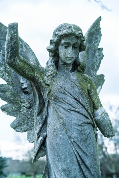 Photo close-up of angel statue in cemetery against sky