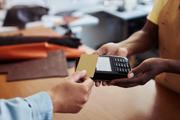 Photo close up of anonymous customer paying with gold credit card in small business shop holding it to ban