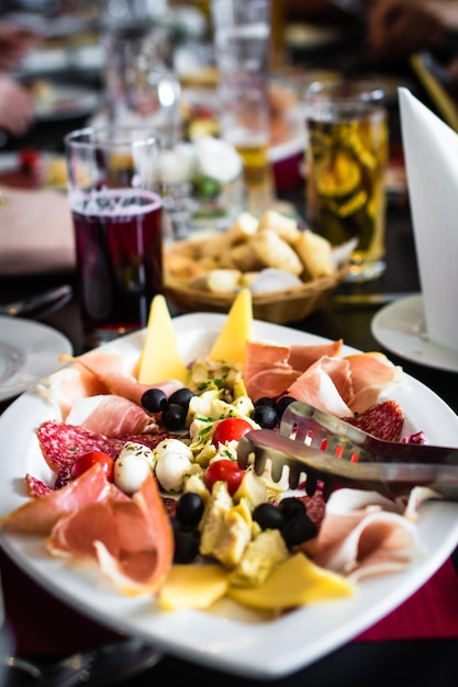 Foto close-up di antipasto con pinze per servire nel piatto sul tavolo al ristorante