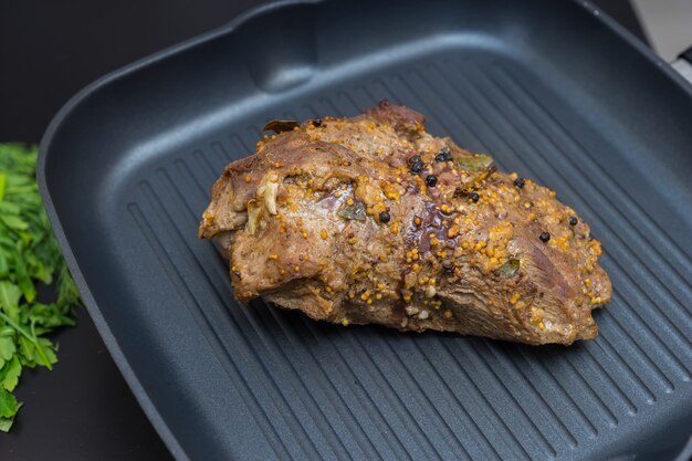 Close up of appetizing prepared marinated meat on a grill pan next to the green parsley