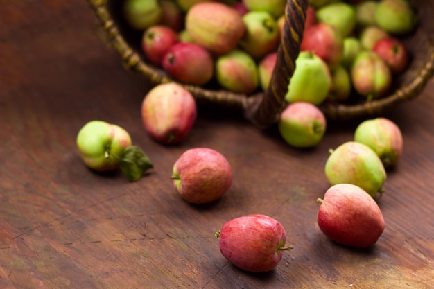 Крупным планом яблок на фоне размытой корзины, полной свежего урожая сладких спелых садовых яблок