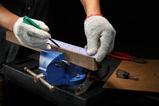 Close-up arbeiders handen op een houten plank opgesloten in de ijzeren bankschroef