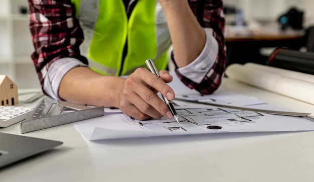 Un primo piano, un architetto, un designer di casa con in mano una penna, che indica una pianta della casa per esaminare il progetto prima di discutere i dettagli con il cliente. idee di design e decorazione d'interni.