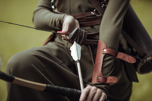 Photo close-up. arrows and bow in female hands. archery man in medieval costume.