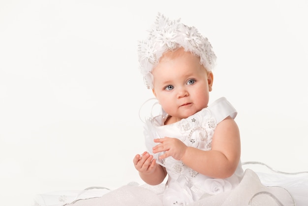 Close-up art portrait of a charming little blue-eyed girl in a white dress