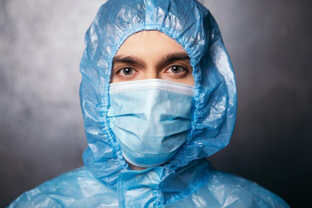 Foto close-up arts die naar de camera kijkt met een beschermend pak en gezichtsmasker