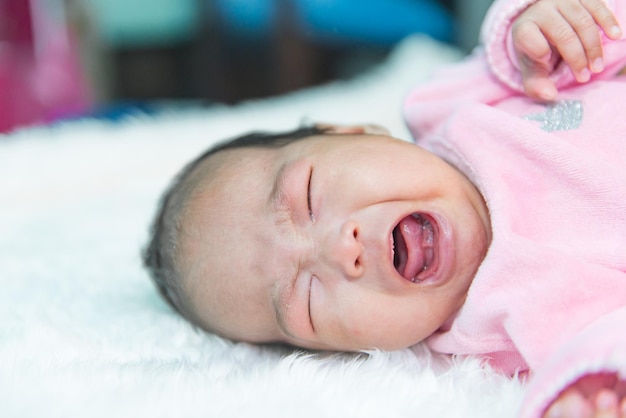 Close up asian baby girl cry on white wool carpet