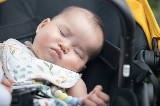 Primo piano sul bambino asiatico che dorme all'interno di un passeggino