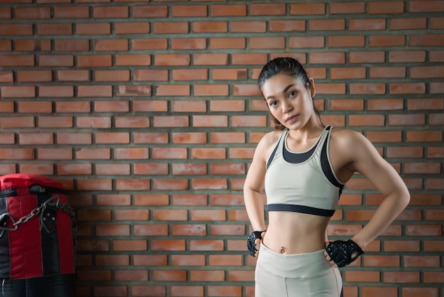 Крупным планом азиатская красивая спортсменка носит спортивный бюстгальтер на стене спортзала. Таиланд любит здоровье. Концепция тренировки стройной женщины.