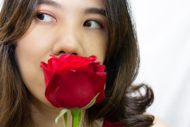 Close up Asian beautiful woman are holding  red rose in front of  her face and look away  A Valentine day and Love