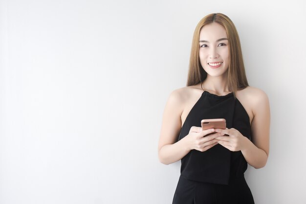 黒いドレスでアジアのビジネス女性を閉じますスマートフォンを笑うと触れる