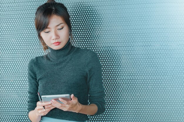 Chiuda in su della donna asiatica di affari che lavora al tablet