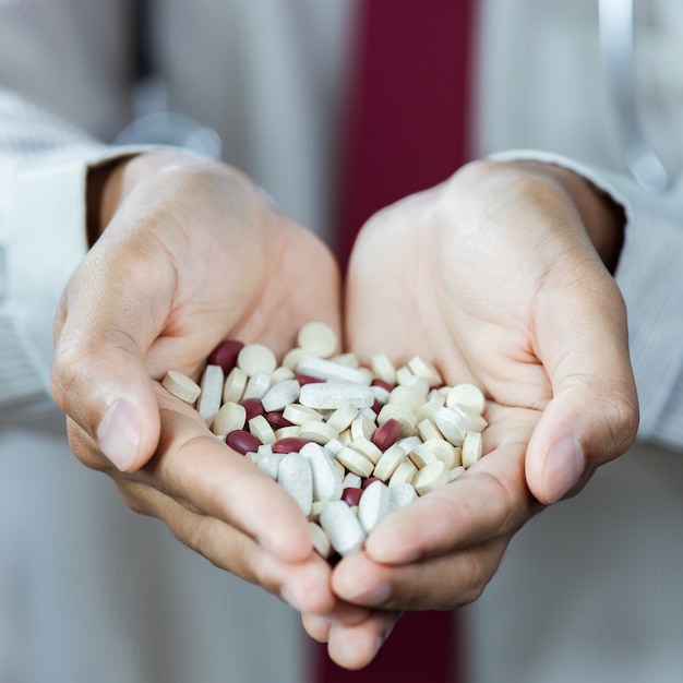 Close-up of asian male doctor displaying a handful of pills in his palm