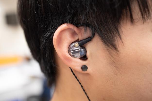 Close-up on asian man ears with earbuds or earphones in his ear