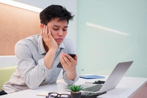 close up asian man feeling bored and sleepy when playing smartphone, lifestyle people concept 