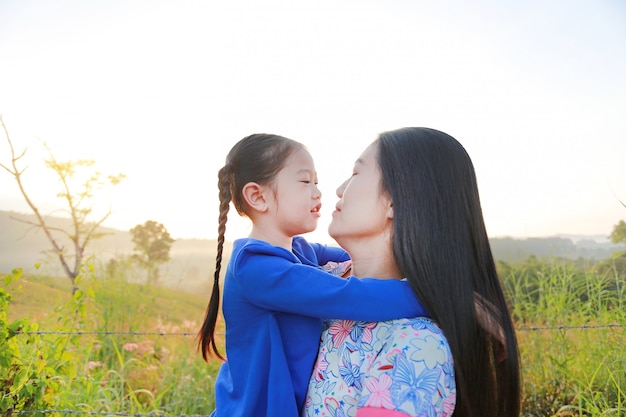 Close up Asian mother and daughters in meadow field at morning sunrise.