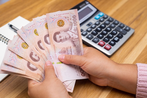 Close up of asian woman with calculator counting money.Woman calculate the spending at home.