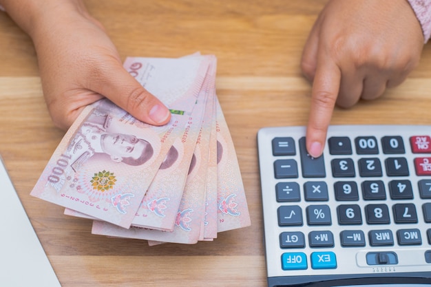 Close up of asian woman with calculator counting money.Woman calculate the spending at home.