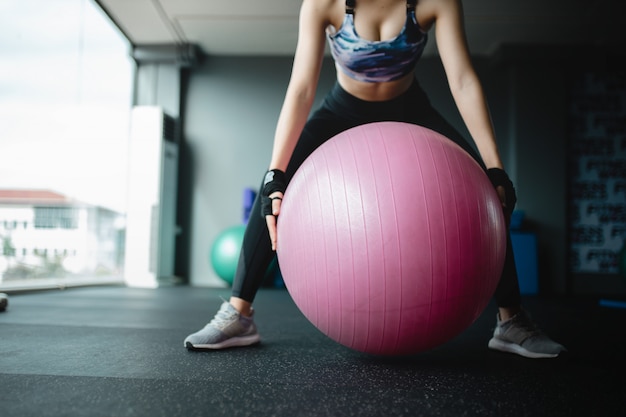 Конец вверх по азиатской модели женщин держит шарик йоги на спортзале подготавливая для тренировки, девушка тренировки