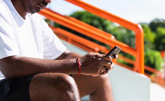 Photo close up asian young athlete sport runner black man wear modern time smart watch and sync to a smartphone check running result after training run at the outdoor, healthy exercise workout technology