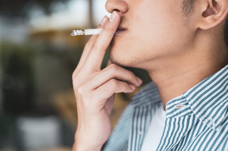 Photo close-up of asian young man smoking a cigarette