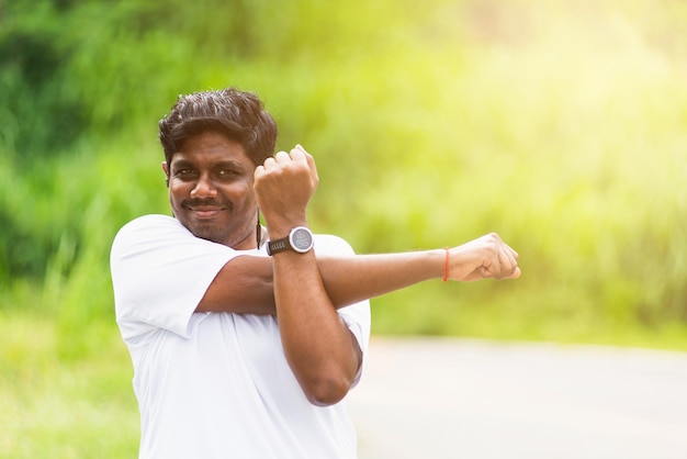 Close up Asian young sport runner black man wear watch he body warming up arms muscles before running at the outdoor street health park, healthy exercise Injury from workout concept