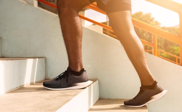 Крупным планом спортивная обувь ног молодой спортивный бегун темнокожий шаг бежит вверх по лестнице, делая тренировку кардио-спорта на улице, здоровые упражнения перед концепцией тренировки