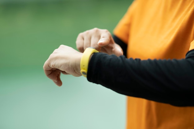 Крупный план спортивной пожилой женщины, проверяющей свои умные часы в парке