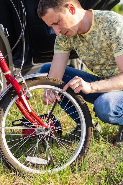 Крупный план привлекательного взрослого мужчины Красивый веломеханик, накачивающий велосипедное колесо Всемирный день велосипеда