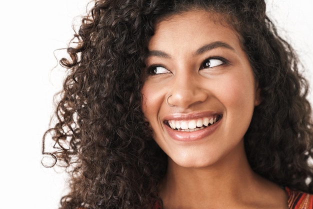 Close up of an attractive cheerful young woman looking away isolated over white wall