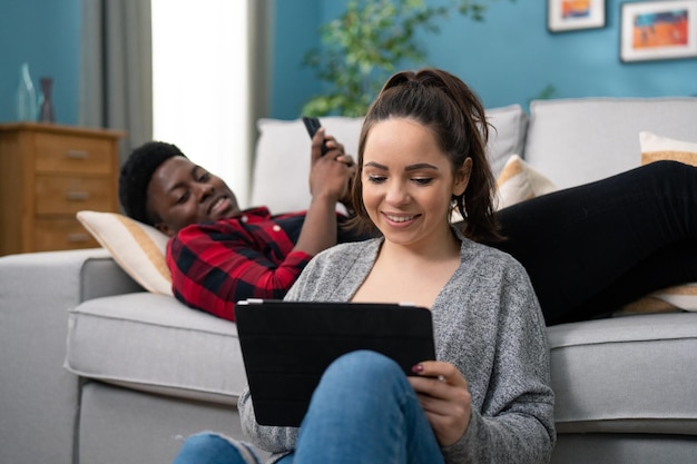 Close up of the attractive smiled caucasian woman showing something on the tablet device to her boyf