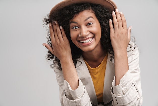 Close up of an attractive smiling young african woman with curly hair, wearing autumn coat and a hat 