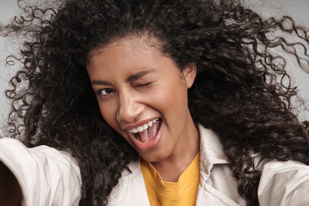 Close up of an attractive smiling young african woman with curly hair, wearing autumn coat 