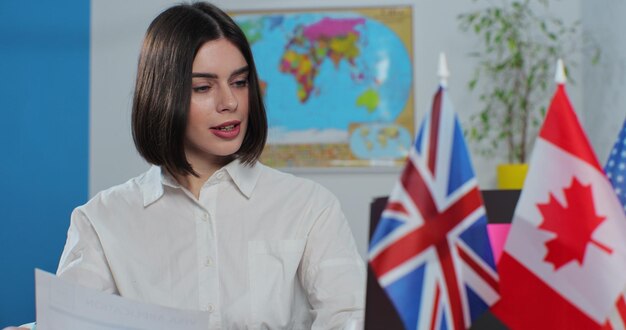 Close up of attractive woman works in a travel agency on laptop computer sitting at a table on the background of a world map Travelling concept