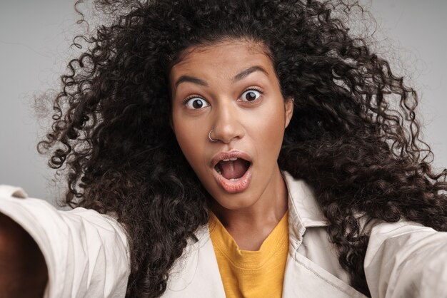 Close up of an attractive young african woman with curly hair, wearing autumn coat 