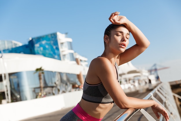 Close-up of attractive young fitness woman leaning on handrail