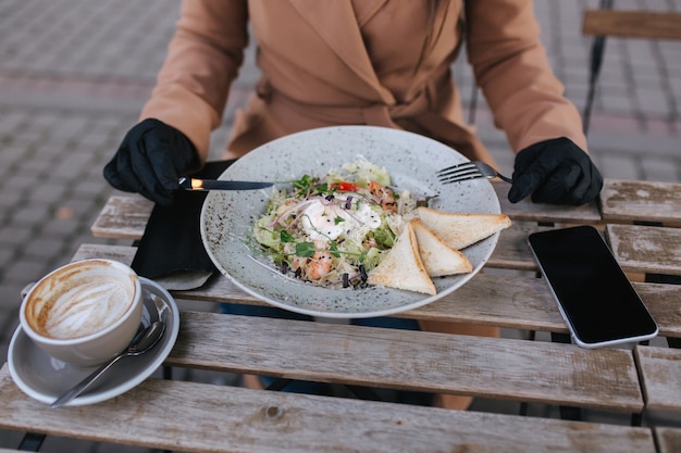 Close up of attractive young woman in black gloves hold cutlery. Cafe concept during qurantine.