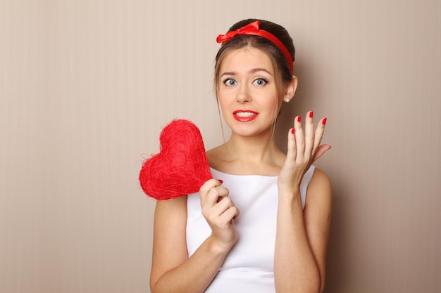 Close up of an attractive young woman holding a red heart