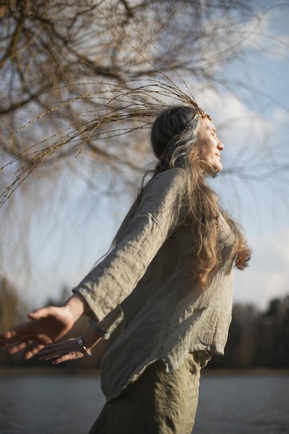 Close up authentic woman with willow crown enjoying warm\
sunlight portrait picture