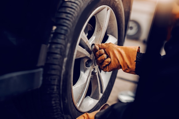 Close up of auto mechanic changing tire in workshop.