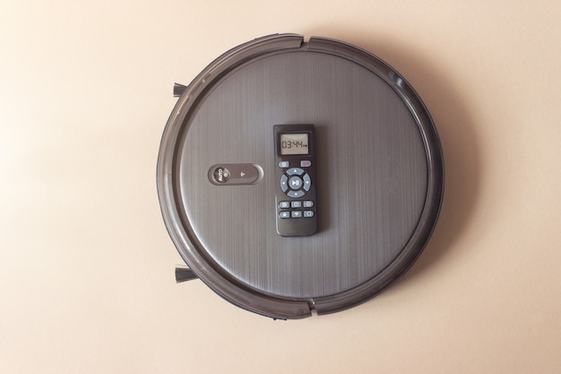 Close-Up Of Autonomous Robot with Remote Control On brown Background. Home cleaning robot.