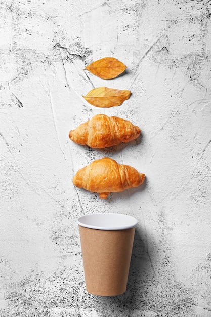 Photo close-up of autumn leaves with croissants and disposable cup on table