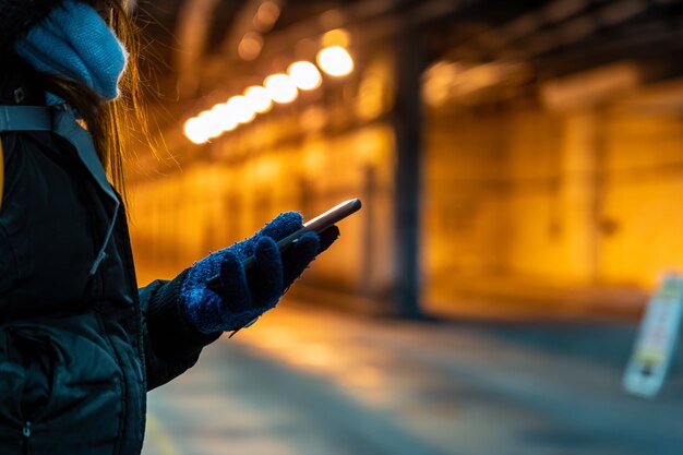 Close-up Aziatische hand die slimme mobiele telefoon in sunwayterminal gebruiken met weinig licht