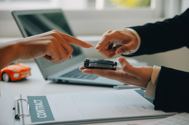 Close-up Aziatische mannelijke autoverkoper of verkoopmanager biedt aan om een auto te verkopen en legt de voorwaarden voor het ondertekenen van een autocontract en verzekering uit en leest deze